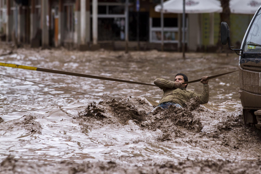 Человек цепляется за веревку, чтобы пересечь затопленную улицу вышедшую из берегов реку Копьяпо,  после обильных осадков, которые затронули некоторые районы города в Копьяпо, Чили.