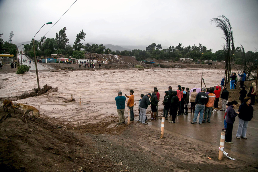 Люди наблюдают за разлитой рекой Копьяпо из-за обильных осадков в городе Копьяпо, Чили