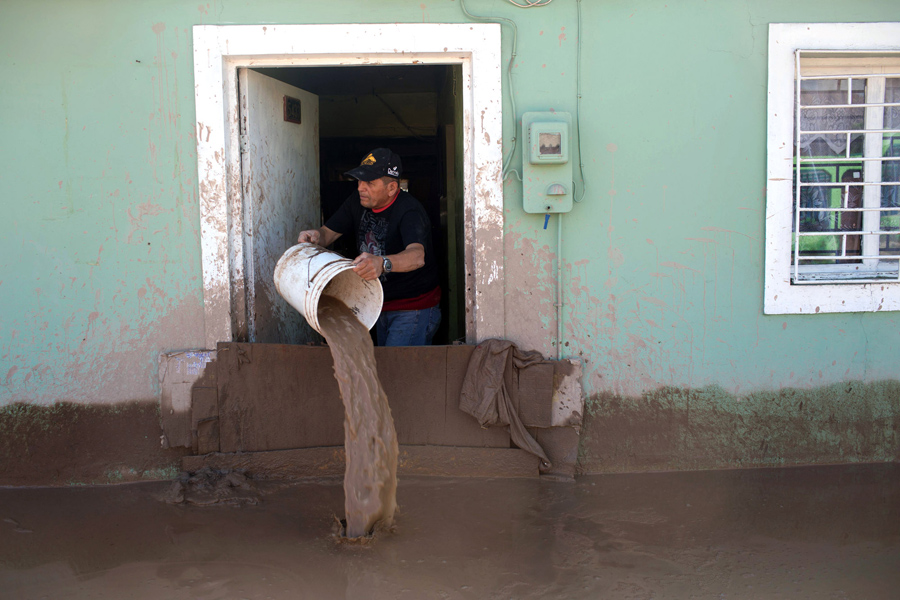 Мужчина опустошает свой дом затоплен проливными дождями в Копьяпо, Чили.