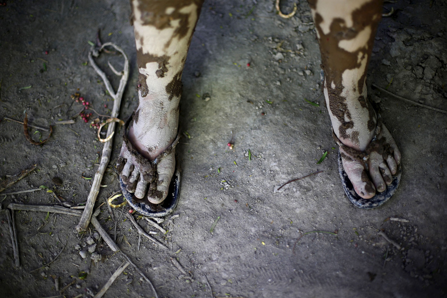 Покрытые грязью ноги ребенка на улице которая пострадала от наводнения в Лос-Лорос, Чили
