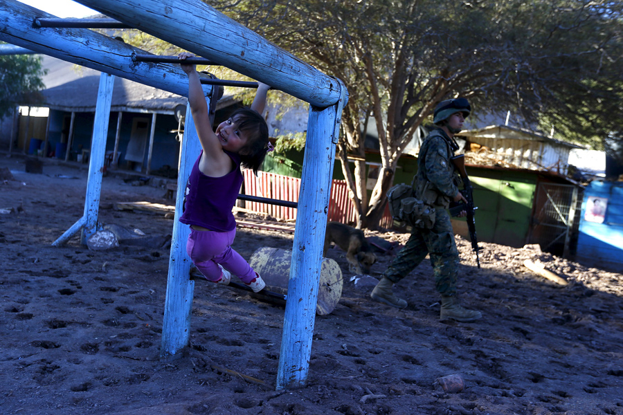 Девочка играет на территории детской площадки, покрытой засохшей грязью в городе Сан-Антонио ( San Antonio), Чили.