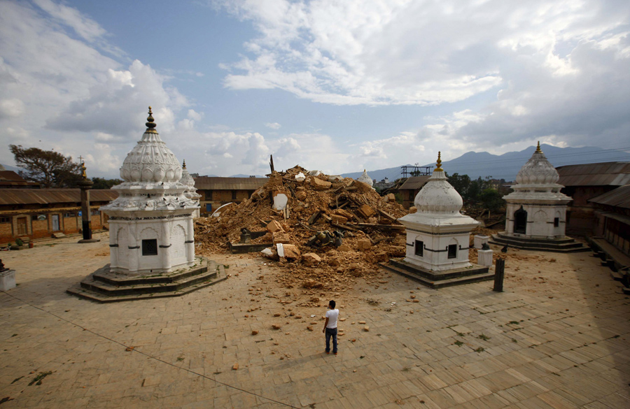 Местные жители смотрят на обломки древнего храма, после того, как он получил повреждение в землетрясении.