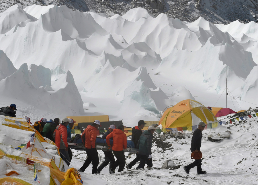 Спасательная команда несет раненого человека в сторону спасательного вертолета в лагерь у Эвереста. 26 апреля 2015 года, после схода лавины, вызванное землетрясением, всё покинули лагерь.