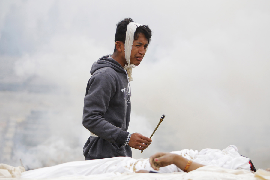 Мужчина выполняет ритуал во время кремации его матери, которая умерла в ходе землетрясения в Бхактапур, рядом с Катманду.