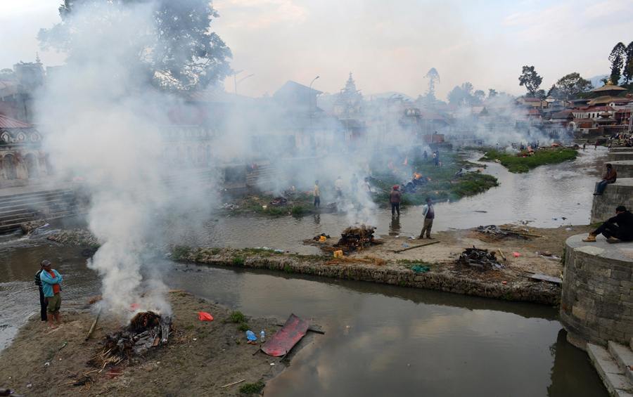 Люди сжигают тела жертв землетрясения, на массовой кремации в Пашупатинатх в Катманду.