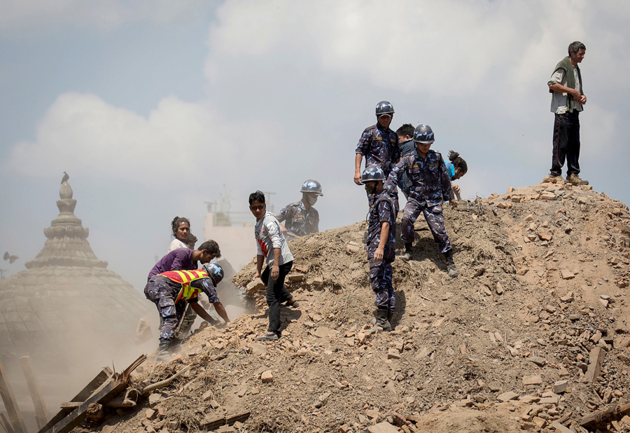 Непальская полиция и добровольцы расчищают развалины, в поисках выживших у разрушенного храма в Катманду.