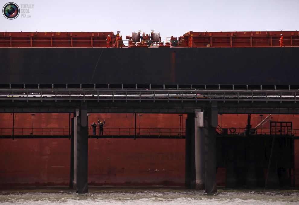 Рабочие в порту грузят судно с углем на РГ Танна угольного терминала расположенном в городе Гладстон в штате Квинсленд, Австралия.