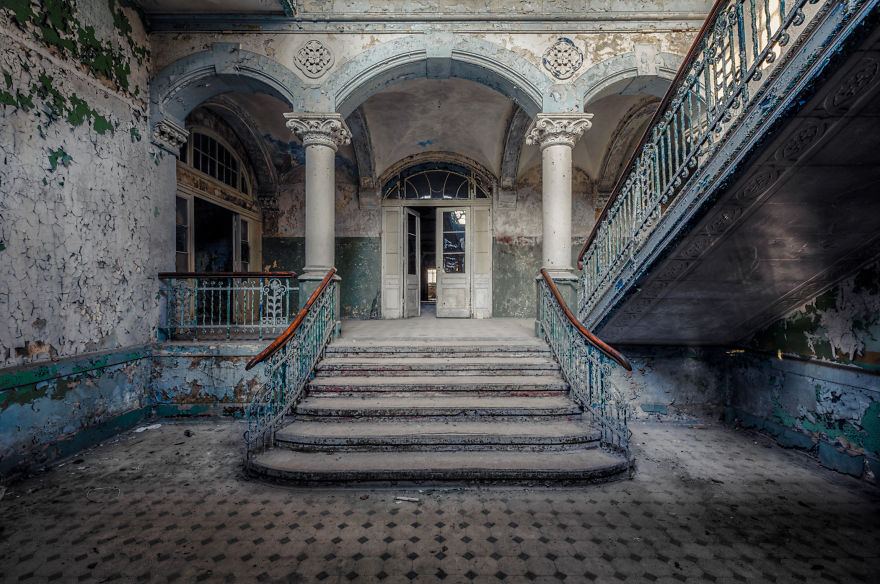 abandoned entry hall with staircase and pillars