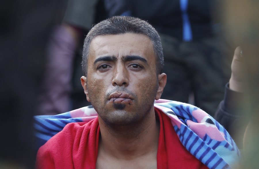 Мигрант с зашитым ртом в знак протеста, сидит на границе с Грецией возле села Гевгелия, Македония, 23 ноября 2015