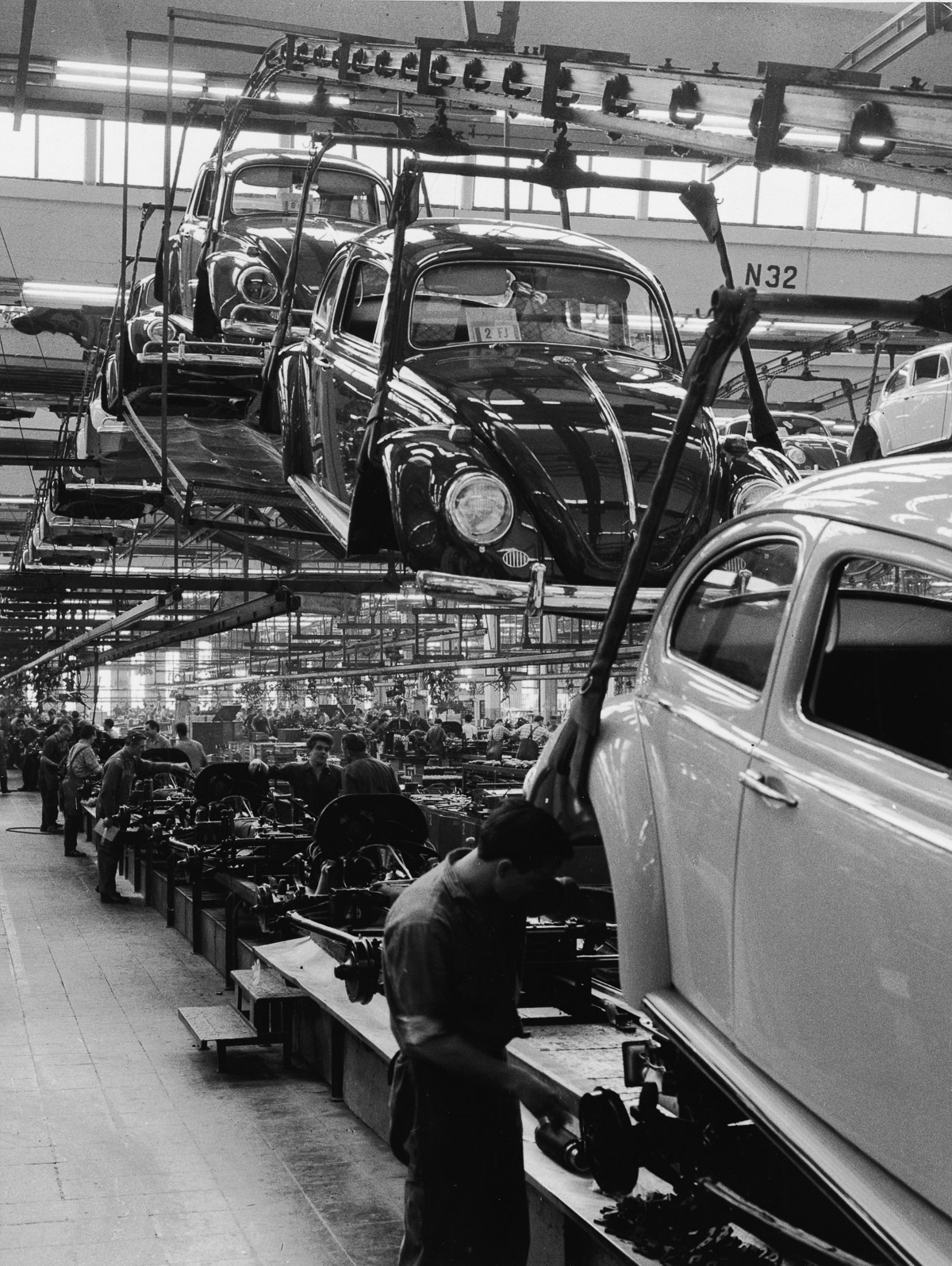 Employees at a Volkswagen plant work on an assembly line to complete Volkswagen 1200 Sedans, better known as Beetles, Wolfsburg, Germany, 1960s. In the foreground, a man guides a car's body as it is lowered onto the chassis. (Photo by Pictorial Parade/Getty Images)