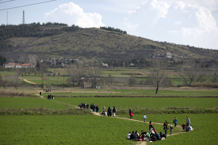 Семьи идут по полю к границе Греция-Македония, 2 марта 2016 года, в Идомени, Греция.