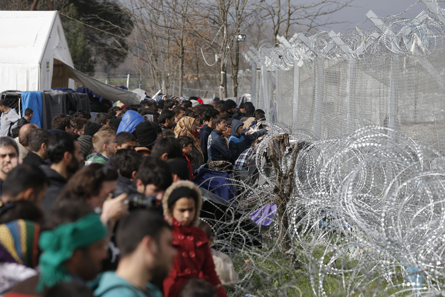 Мигранты стоят рядом с забором греко-македонской границы, 1 марта 2016 года.