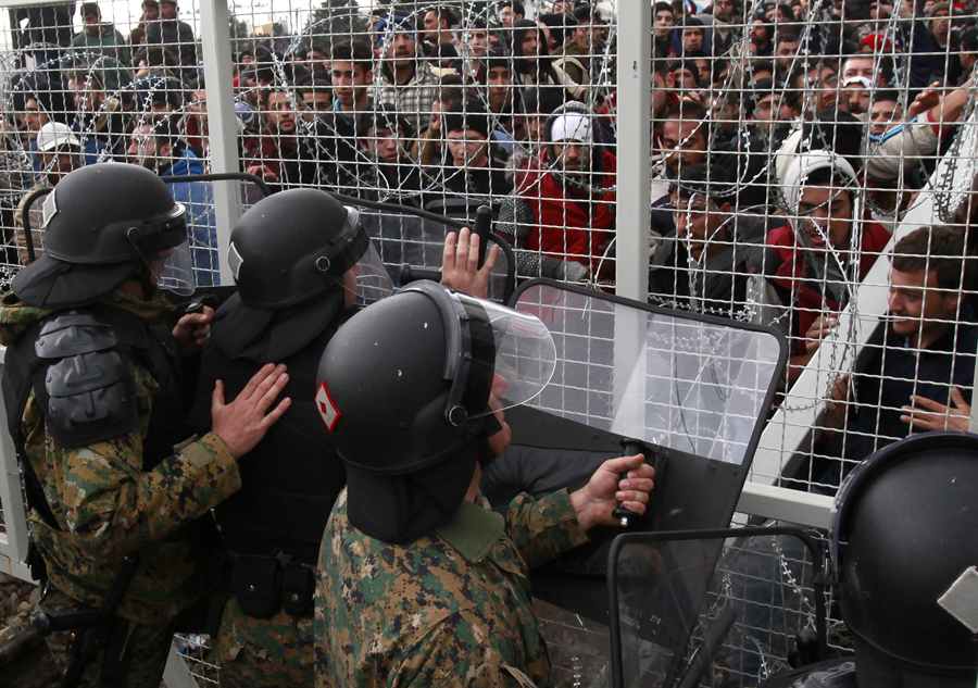 Беженцы и мигранты пытаются сломать забор на греческую границу, македонская полиция сдерживает их, возле южного македонского города Гевгелия, 29 февраля 2016 года.