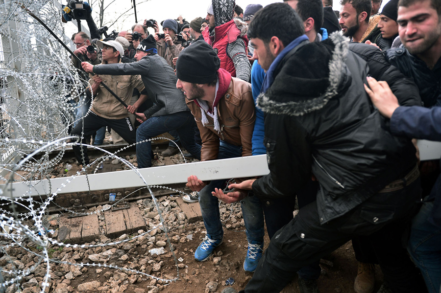 Мигранты пытаются прорваться через пограничный забор в Македонию близ городка Идомени, 29 февраля 2016 года.