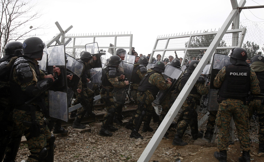 Мигранты пытаются прорваться через пограничный забор, македонская полиция толкает их обратно, возле Гевгелии, 29 февраля 2016 года.