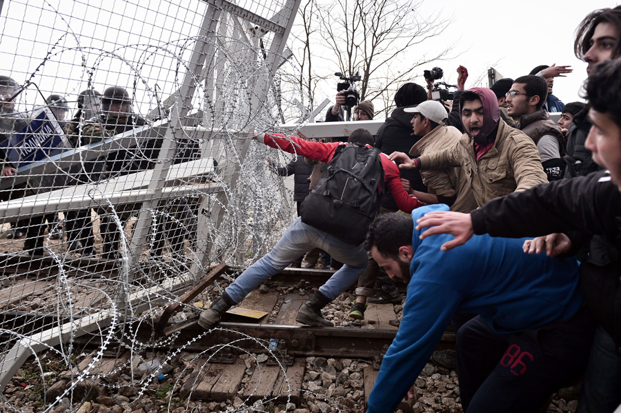Мигранты пытаются прорваться через пограничный забор в Македонию около Идомени, 29 февраля 2016 года.