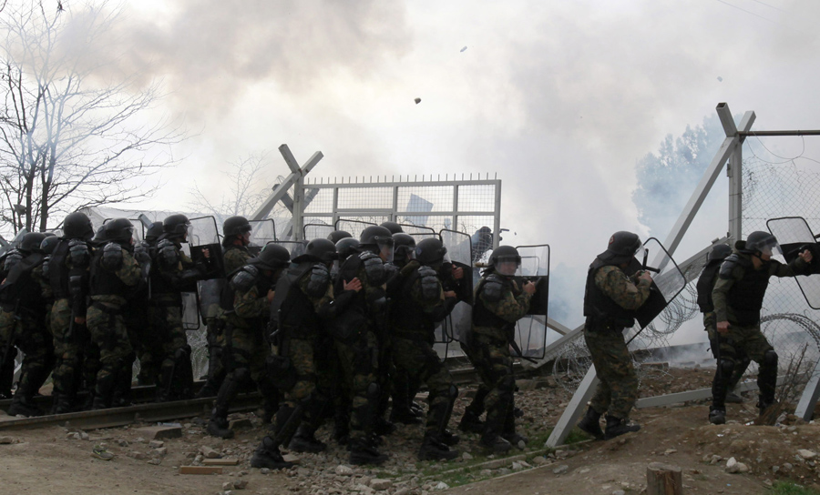 Приезжие разорвали пограничный забор и бросают камни с греческой стороны, македонские полицейские используют слезоточивый газ, 29 февраля 2016 года.