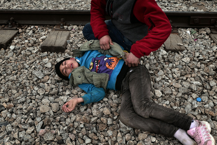 Мужчина помогает мальчику который упал после того как вдохнул слезоточивый газ. Македонская полиция применила слезоточивый газ на сотнях иракских и сирийских мигрантов, которые пытались прорваться через греческий пограничный забор в Идомени, 29 февраля 2016 года.