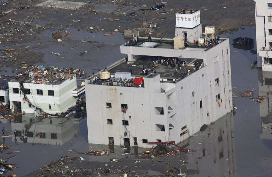 Люди спасаются на крыше здания в поселке Минамисанрику, Мияги, Япония после катастрофического землетрясения и цунами.