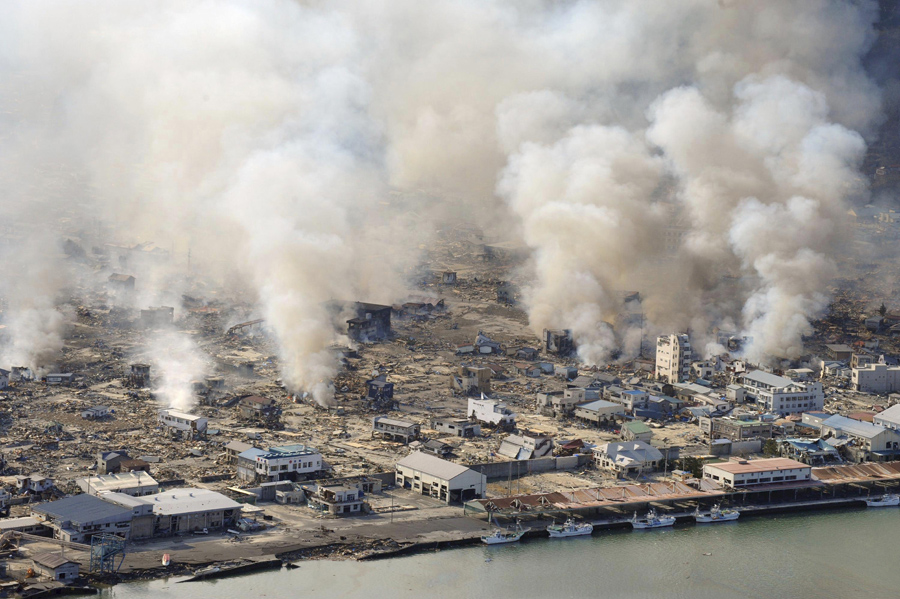 Дым поднимается в небо от горящих зданий в поселке Ямада префектуры Иватэ, 12 марта 2011, на следующий день после землетрясения и цунами.