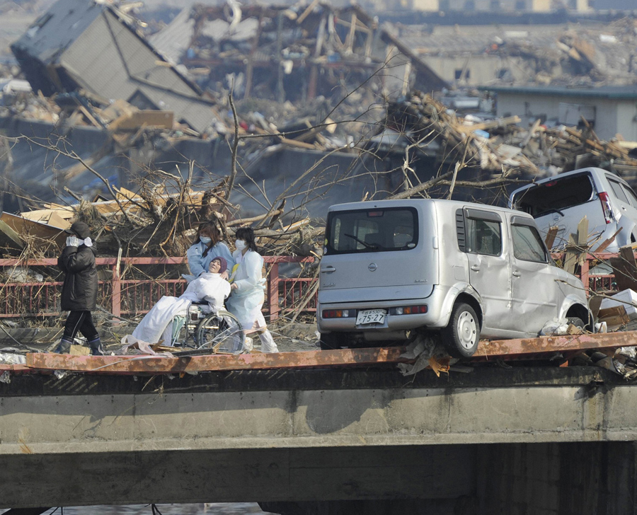 Женщину эвакуировали из разрушенной больницы в поселке Оцути, префектура Иватэ, 13 марта 2011 года.