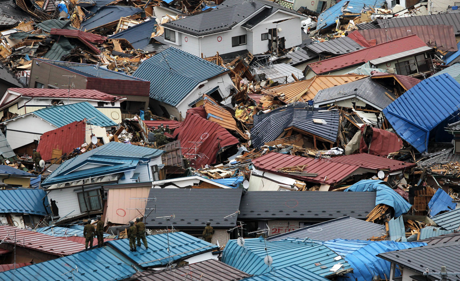 Спасатели ходят среди разрушенных домов и кораблей, все было уничтожено цунами в Мияко, 15 марта 2011 года.