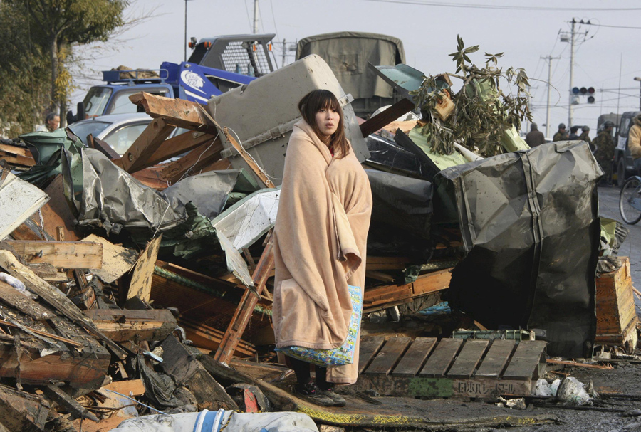 Женщина смотрит на разрушения вызванные цунами и землетрясение в городе Исиномаки, префектура Мияги, 13 марта 2011.