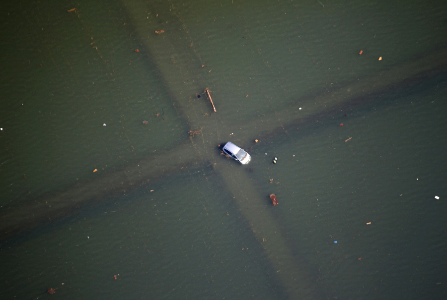 Полузатопленный автомобиль на перекрестке после землетрясения и цунами в Сендае, 12 марта 2011.