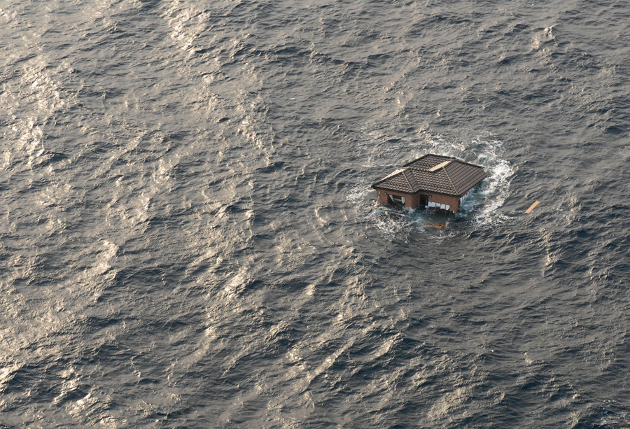 Японский дом плавает в Тихом океане, 13 марта 2011 года. В прибрежных водах возле г. Сендай, Япония.