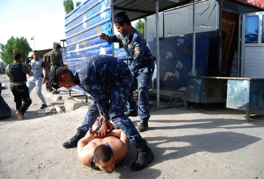 Иракский полицейский Саад Али Табита задерживает горе-смертника на контрольно-пропускном пункте к северу от Багдада, 25 мая 2016 года. 