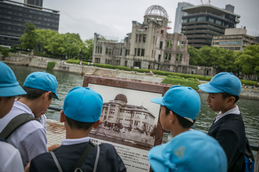 26 мая 2016 года, школьники смотрят на старую фотографию купола выставочного центра до взрыва атомной бомбы в Хиросиме, Япония.