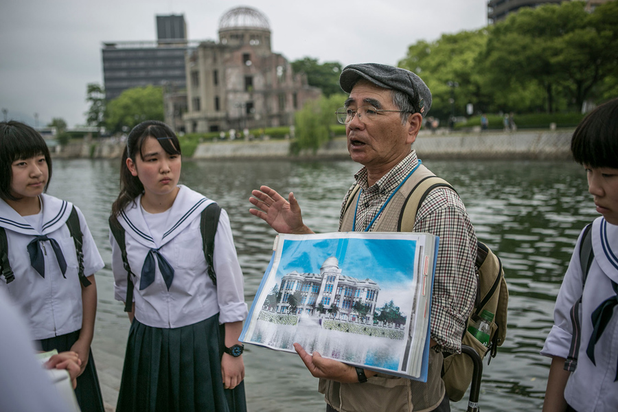 Руководитель группы выживших показывает для учащихся средних школ фотографию купола выставочного центра до атомной бомбардировки, 26 мая 2016 года.