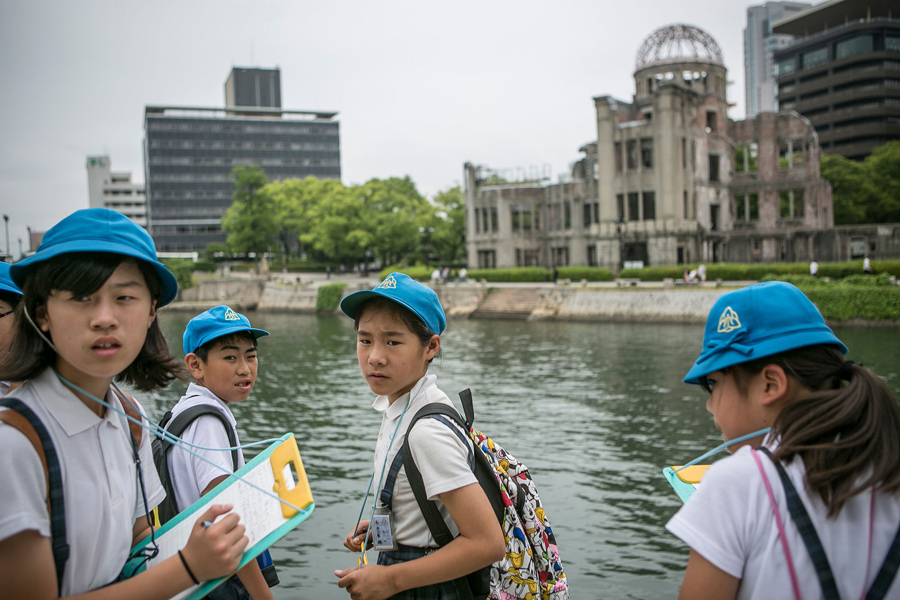 Школьники делают пометки и слушают гида, на месте разрушенного купола после падения атомной бомбы, 26 мая 2016 года в Хиросиме, Япония.