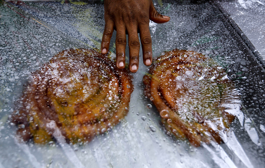 Еду накрывают полиэтиленовой пленкой, чтобы сохранить её от дождя во время священного месяца в первый день Рамадана, Дакка, Бангладеш, 7 июня 2016 года.