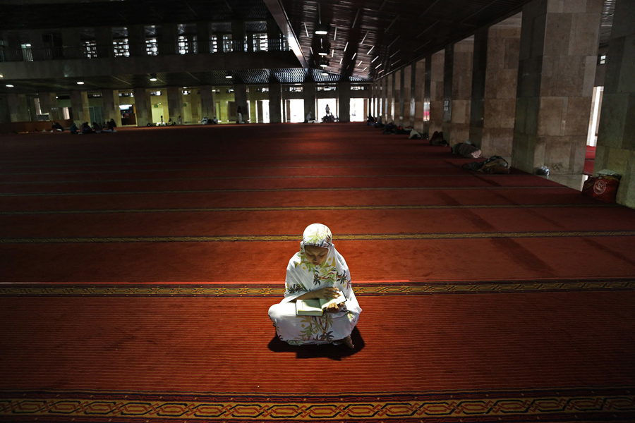 Мусульманка читает Коран в полдень после молитвы, первый день Рамадана в мечети Истикляль что в Джакарте, Индонезия, 6 июня 2016 года.