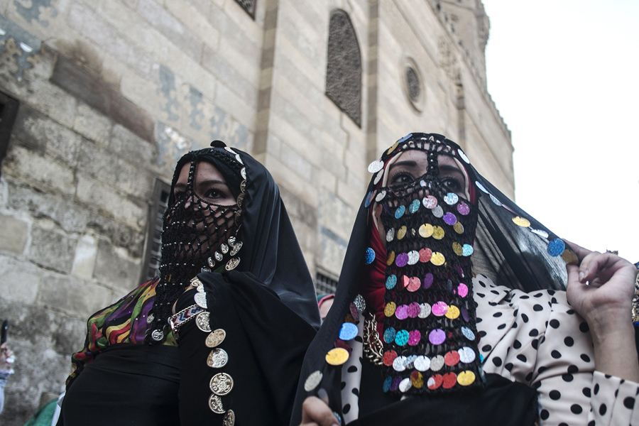 Египетские женщины, одетые в традиционную одежду прогуливаются по улице Аль-Мес во время празднования преддверии священного для мусульман месяца Рамадан в старом Каире, 2 июня 2016 года.