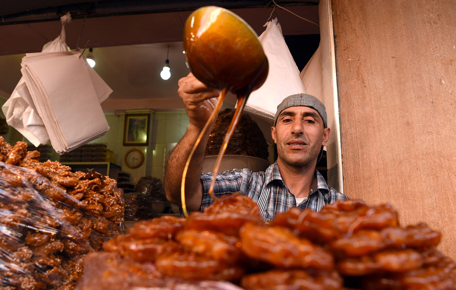 Продавец - кондитер наливает мед на выпечку Chebakia до начала Рамадана, 6 июня 2016 года в старой Медине Рабата, Марокко.