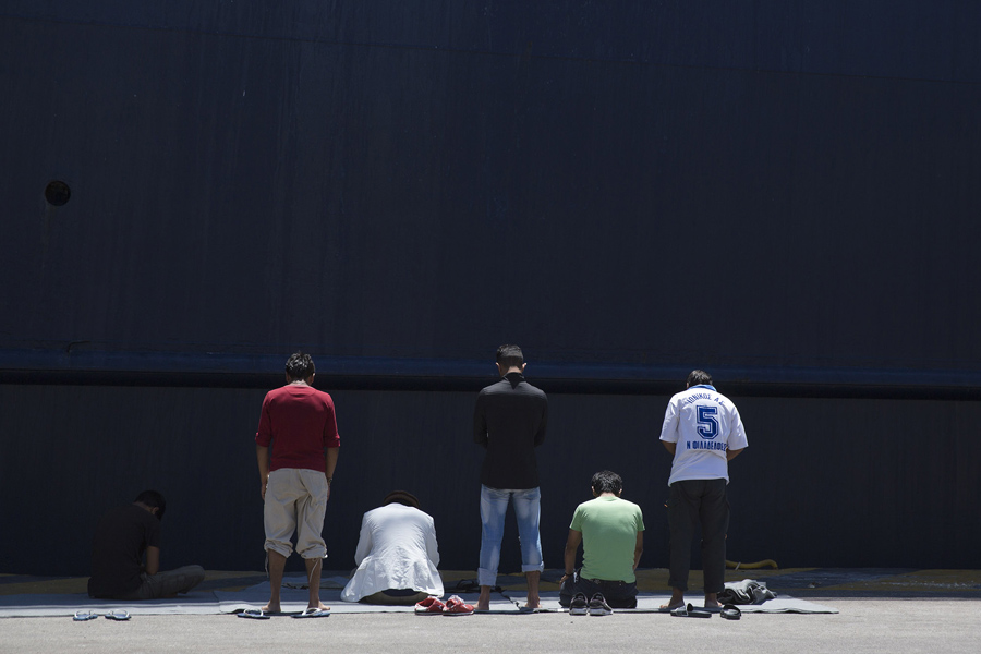 Афганские мигранты в Греции молятся перед пришвартовавшимся паромом в порту Пирей, недалеко от Афин, 6 июня 2016 года.