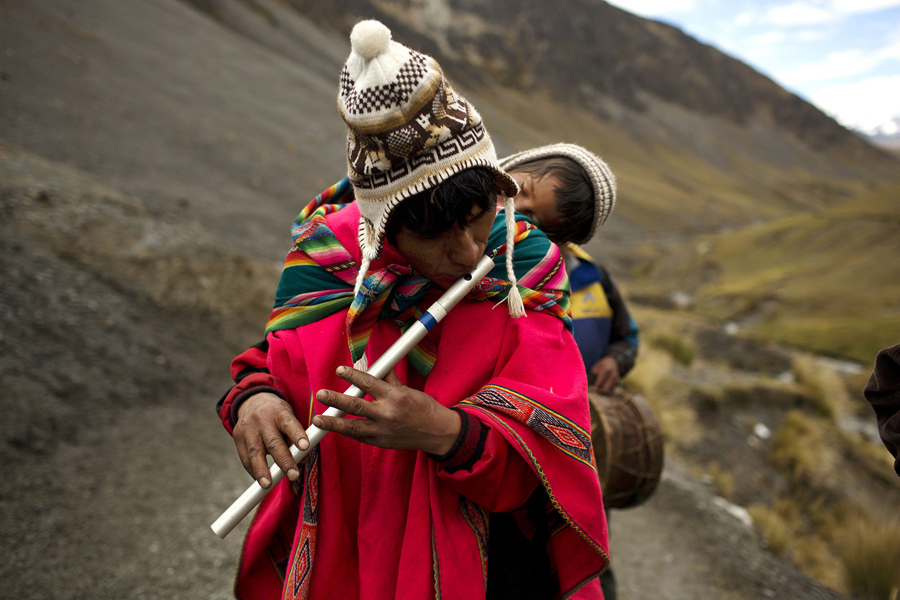 Мужчина со своим сыном играет на традиционной Андской флейте.