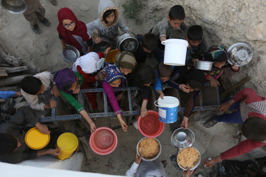 Афганские жители получают бесплатное питание, пожертвованные другими сельскими жителями, поскольку они готовятся завершить пост в Кабуле, Афганистан, 9 июня 2016 года.
