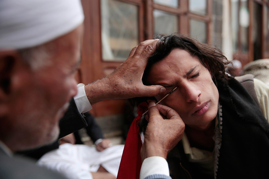 Человек наносит косметическое средство сурьма или кохл на веко в соборной мечети старого города Сане, Йемен, 23 июня 2016 года. Кохл используется на Ближнем Востоке в качестве защиты от глазных болезней.