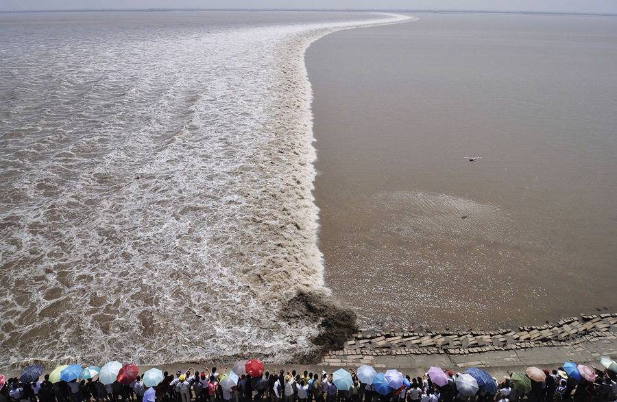 Фотография с вертолёта который парит над рекой Цяньтан. Туристы собираются на берегу чтобы увидеть прилив, 13 сентября 2011 года.