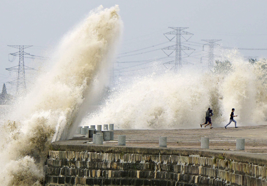 Люди бегут от воды вызванных приливной волной которая хлынули мимо барьера на берегу реки Цяньтан, в Ханчжоу, 8 октября 2014 г.