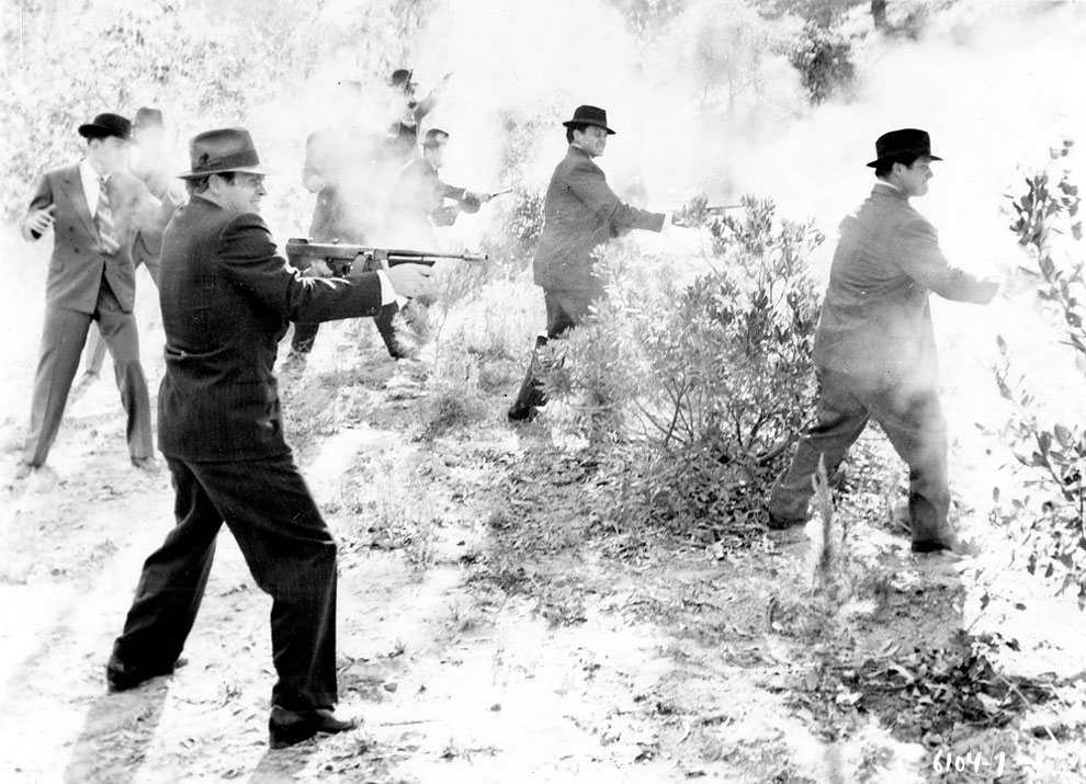 Группа гангстеров в костюмах и головных уборах тренируются в стрельбе из Томпсона, пистолетов - пулеметов, дробовиков и револьверов, США, 1930 - е годы.