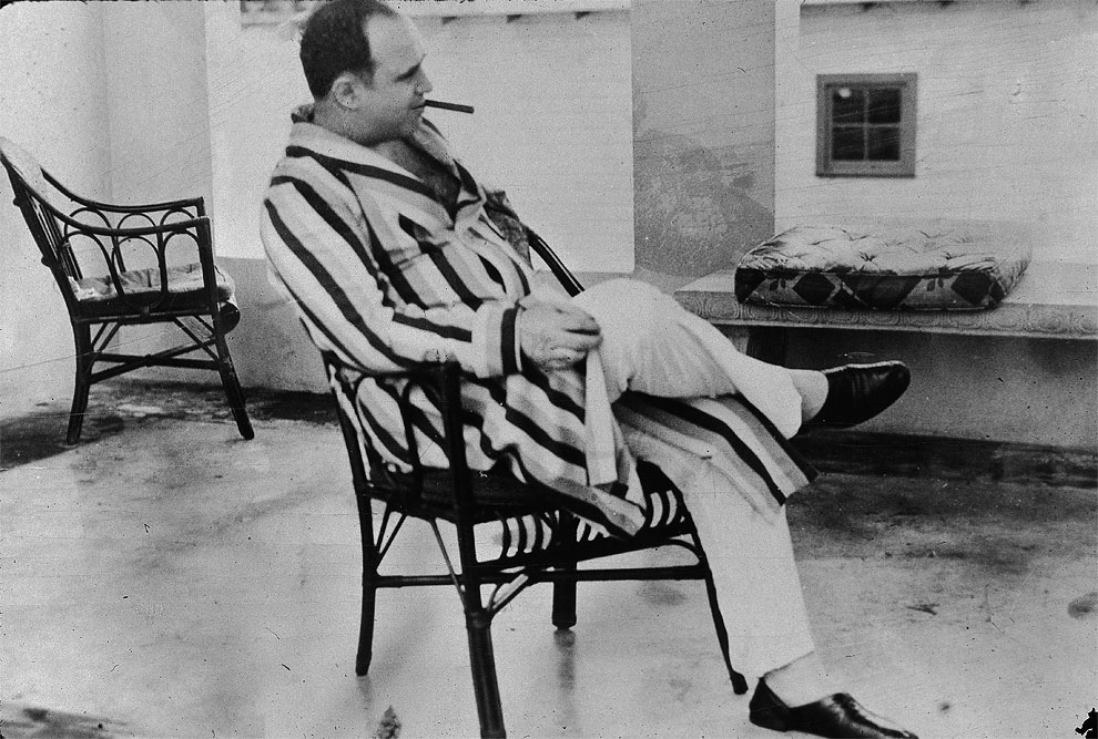 Американский гангстер Аль Капоне ( "Scarface") (1899 - 1947) отдыхает в своем доме в Майами, Флорида, 1930 г. Капоне курит сигары и носит полосатый халат.
