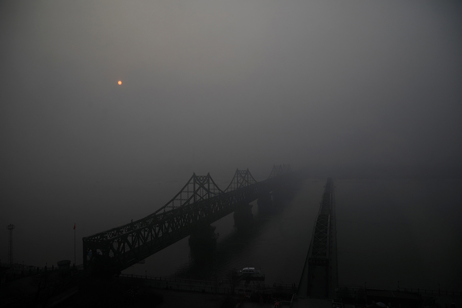 Солнце поднимается сквозь туман над разбитым мостом через реку Ялу , соединяющими Северную Корею и Китай, 30 марта 2017.