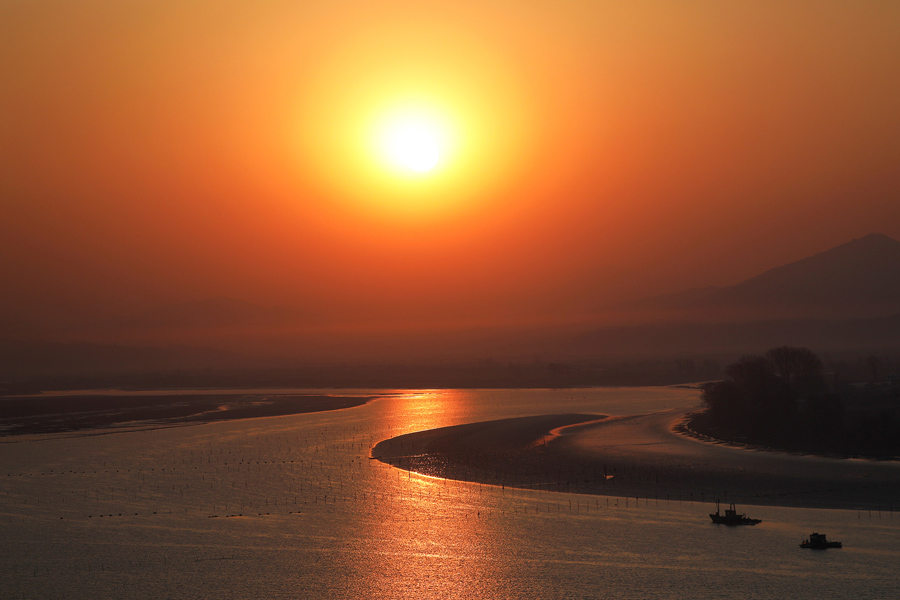 Солнце поднимается с северокорейской стороны реки Ялу недалеко от города Синыйджу, вид из Даньдуна, Китай, 1 апреля, 2017.