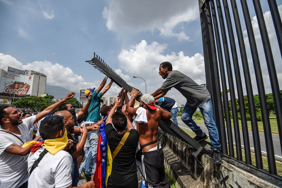 Демонстранты пытаются снести забор на авиабазе Ла Карлота во время митинга против президента Венесуэлы Мадуро, Каракас, 19 апреля, 2017.