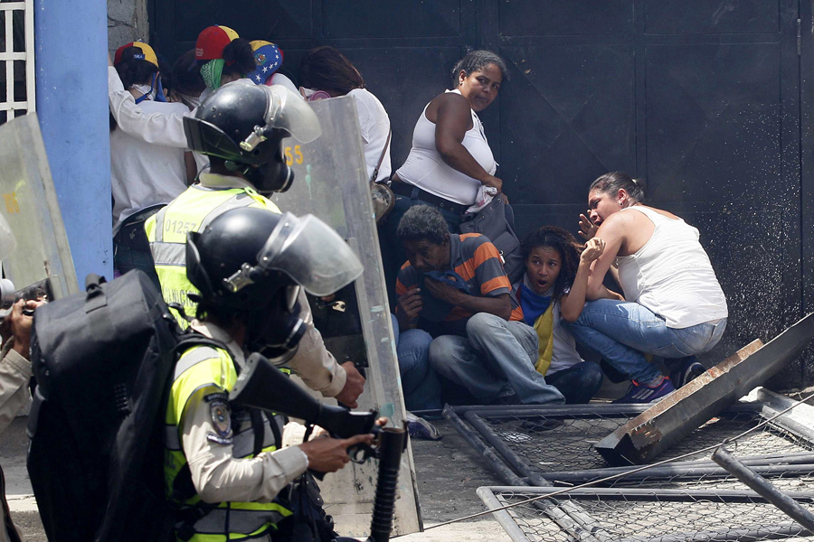 Антиправительственные демонстранты укрываться от полиции во время протестов в Каракасе 19 апреля 2017 года.