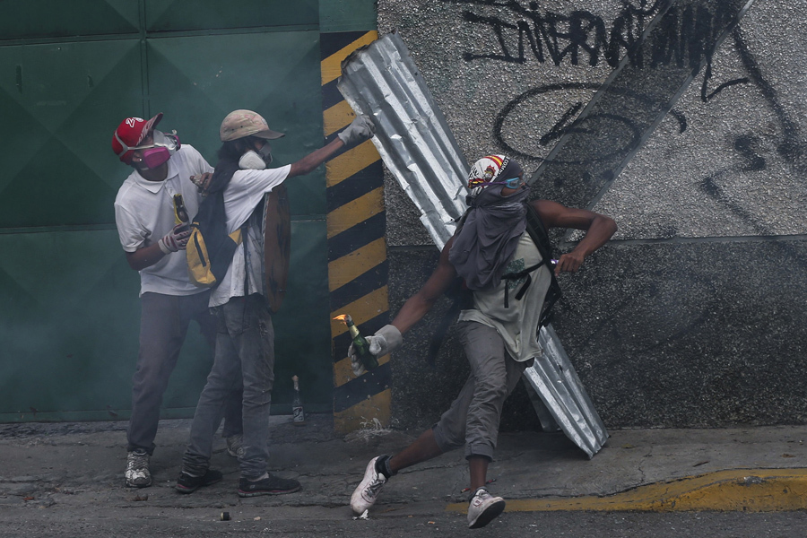 Мужчина бросает коктейль Молотова в полицию, Каракас 19 апреля 2017 года.